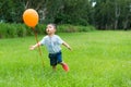 Little boy running to catch with orange balloon Royalty Free Stock Photo