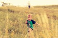 Little boy runs across the field through the grass at sunset Royalty Free Stock Photo