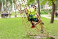 Little boy in safety equipment climbing on rope wall at adventure park. Children summer sport extreme outdoor activity. Back view