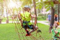 Little boy in safety equipment climbing on rope wall at adventure park. Fiend making a photo shot on smartphone. Children summer s Royalty Free Stock Photo