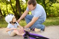 Little boy in safety helmet falls during learning to ride scooter. Royalty Free Stock Photo