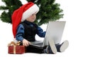 Little boy in Santa Claus cap with a laptop and Christmas gift Royalty Free Stock Photo