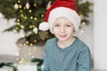 Little boy in santa hat. Portrait of beautiful kid in christmas clothing in front of a decorated christmas tree Royalty Free Stock Photo