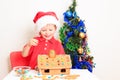 Little boy in Santa's hat building gingerbread