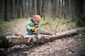 Little boy sawing a fallen tree in the forest