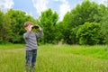 Little boy scanning the woods with binoculars