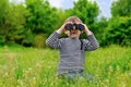 Little boy scanning the woods with binoculars