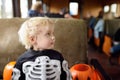 Little boy in scary costume skeleton ride in traditional train express on celebrations halloween