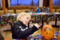 Little boy in scary skeleton costume paints pumpkin on halloween party for children