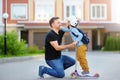 Little boy with scooter says goodbye and hugging to his father before going to school. Education for children. First day of school