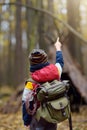 Little boy scout with binoculars during hiking in autumn forest. Teepee hut on background