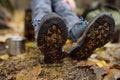 Little boy scout during hiking in autumn forest. Child is resting on large fallen tree and drinking hot tea. Legs close-up