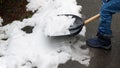 Little boy is shown clearing the backyard or walkway from snow with a shovel after a snowstorm or blizzard. The concept of winter
