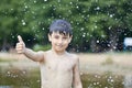 A little boy shows a thumbs up like in the middle of frozen water droplets in the air Royalty Free Stock Photo