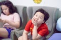 Little boy sit on sofa chair with sister at room home with boredom face expression Royalty Free Stock Photo