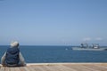 Little boy sits alone and looks at the ships in the sea Royalty Free Stock Photo