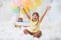 A little boy sits in a balloon basket in the clouds, pretending to travel and fly with an Aviator hat for a concept of creativity Royalty Free Stock Photo