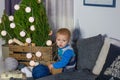 A little boy sits by the Christmas tree in anticipation of holiday