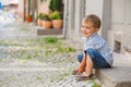 Little boy sits on the doorstep on a city street Royalty Free Stock Photo