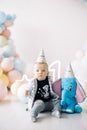 Little boy sits on the floor next to the balloons and toy elephant, celebrating its first birthday Royalty Free Stock Photo