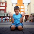 A little boy sits on the ground with his hands up and protests. The concept of raising a difficult naughty child. Royalty Free Stock Photo