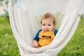 A little boy sits in a hammock and looks at the camera on a summer day in the garden Royalty Free Stock Photo