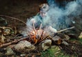 Little boy sits near campfire