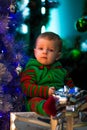 Little boy sits near Christmas tree and gift boxes. Royalty Free Stock Photo