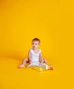 A little boy sits in a T-shirt and underpants next to a big gift box