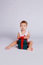 A little boy sits in a T-shirt and underpants next to a big gift box