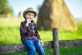 Little boy sits on wooden fence against picturesque haystack Royalty Free Stock Photo