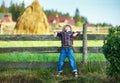 Little boy sits on wooden fence against picturesque haystack Royalty Free Stock Photo