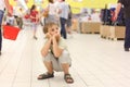 Little boy sitting alone on hunkers in big store Royalty Free Stock Photo