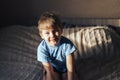 Little boy is sitting on the bed. The sun\'s rays fall on the child. Good parenting Royalty Free Stock Photo