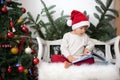 Little boy, sitting on a bench under christmas tree, eating choc Royalty Free Stock Photo