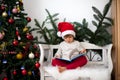 Little boy, sitting on a bench under christmas tree, eating choc Royalty Free Stock Photo