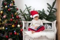 Little boy, sitting on a bench under christmas tree, eating choc Royalty Free Stock Photo