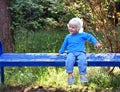 little boy sitting on the blue bench in the park Royalty Free Stock Photo