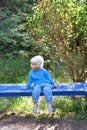 little boy sitting on the blue bench in the park Royalty Free Stock Photo