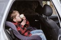 Little boy, sitting in a car and drinking from a thermos mug . Car seat for children Royalty Free Stock Photo