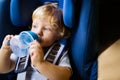 Little boy sitting in the car seat in the car, drinking. Royalty Free Stock Photo