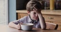 Little boy sitting at dining table feels sluggish without appetite
