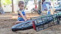 Little boy sitting in the dirt playing with a bike wheel