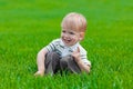 Little boy sitting and dreaming in green grass Royalty Free Stock Photo