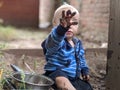 Little boy sitting on the ground holding up his muddy hand