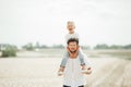 Little boy is sitting on his father shoulders a in the wheat field