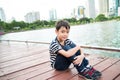 Little boy sitting nearby the lagoon in the pard alone