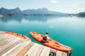 Little boy sitting on orange kayak near the pier and dangling feet making radial waves on Cheow Lan Lake, Khao Sok national park, Royalty Free Stock Photo