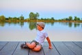 Little boy sitting on pier. Elementary age boy sitting on a wooden pier. Summer and childhood concept. Child on bench at the lake. Royalty Free Stock Photo