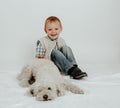 A little boy is sitting, playing with a white dog Royalty Free Stock Photo